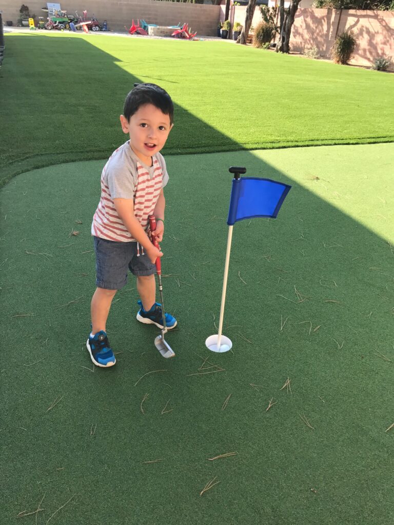Child practicing chipping on a backyard putting green