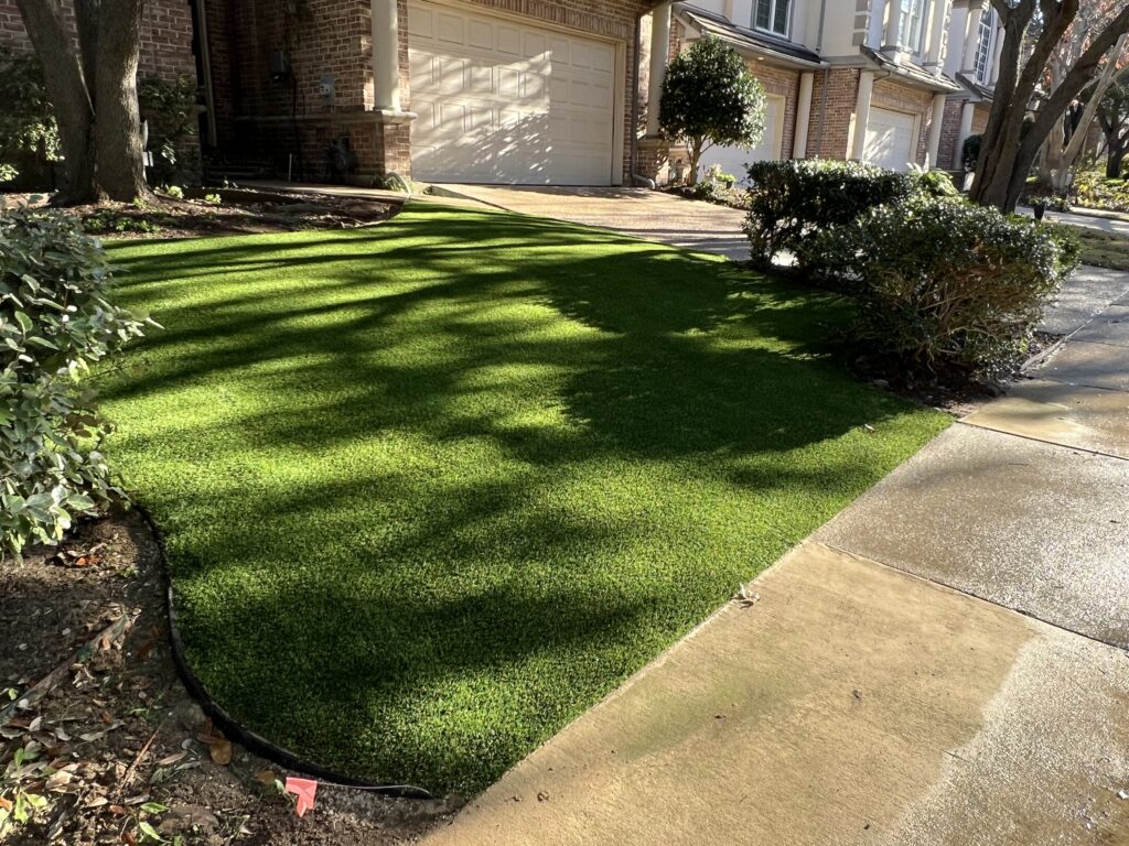 Artificial turf meeting a natural yard edge along a driveway