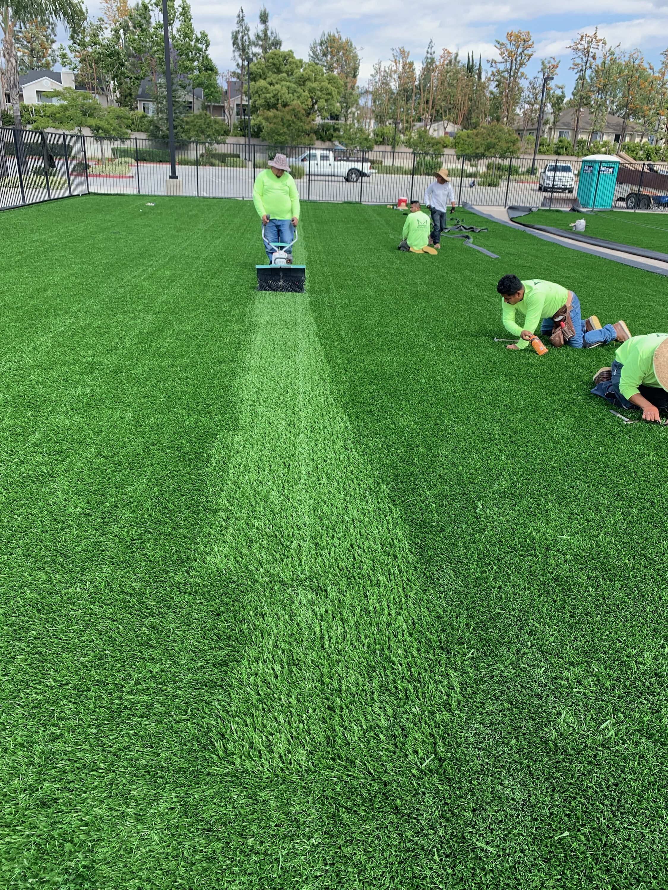 Sports field installation crew brushing - Green Forever Turf Texas